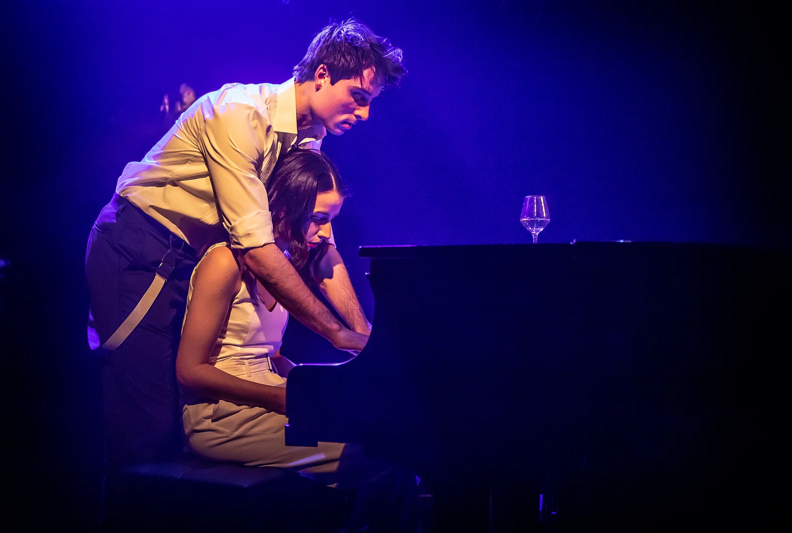 Two performers playing a piano together under blue stage lighting in The Last Five Years at Southwark Playhouse.